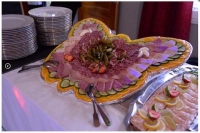 Plateau de charcuterie en forme de papillon, décoré de légumes, cornichons et fraises, avec assiettes empilées à côté.