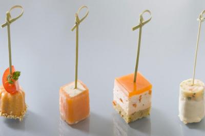 Traiteur Auberge de La Herse Bonneval #2 Quatre amuse-bouches variés présentés sur des piques en bois, disposés sur une surface lisse et claire.