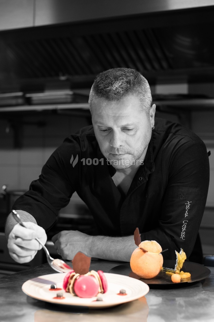 Un chef pâtissier décorant des desserts raffinés dans une cuisine professionnelle.