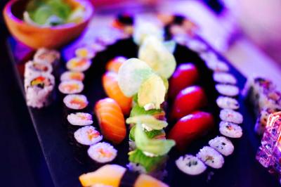 Traiteur Maître Sushi Traiteur Événementiel Lyon  Saint-Priest #3 Plateau de sushis variés avec makis, sashimis et chips, présenté sur une table éclairée par une lumière colorée.