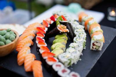 Traiteur Maître Sushi Traiteur Événementiel Lyon  Saint-Priest #4 Assortiment de sushis variés disposés sur une ardoise, avec des garnitures colorées et une coupe de wasabi à côté.