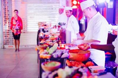 Traiteur Maître Sushi Traiteur Événementiel Lyon  Saint-Priest #1 Des chefs préparent des plats sur un buffet garni de mets variés dans un espace lumineux et animé.