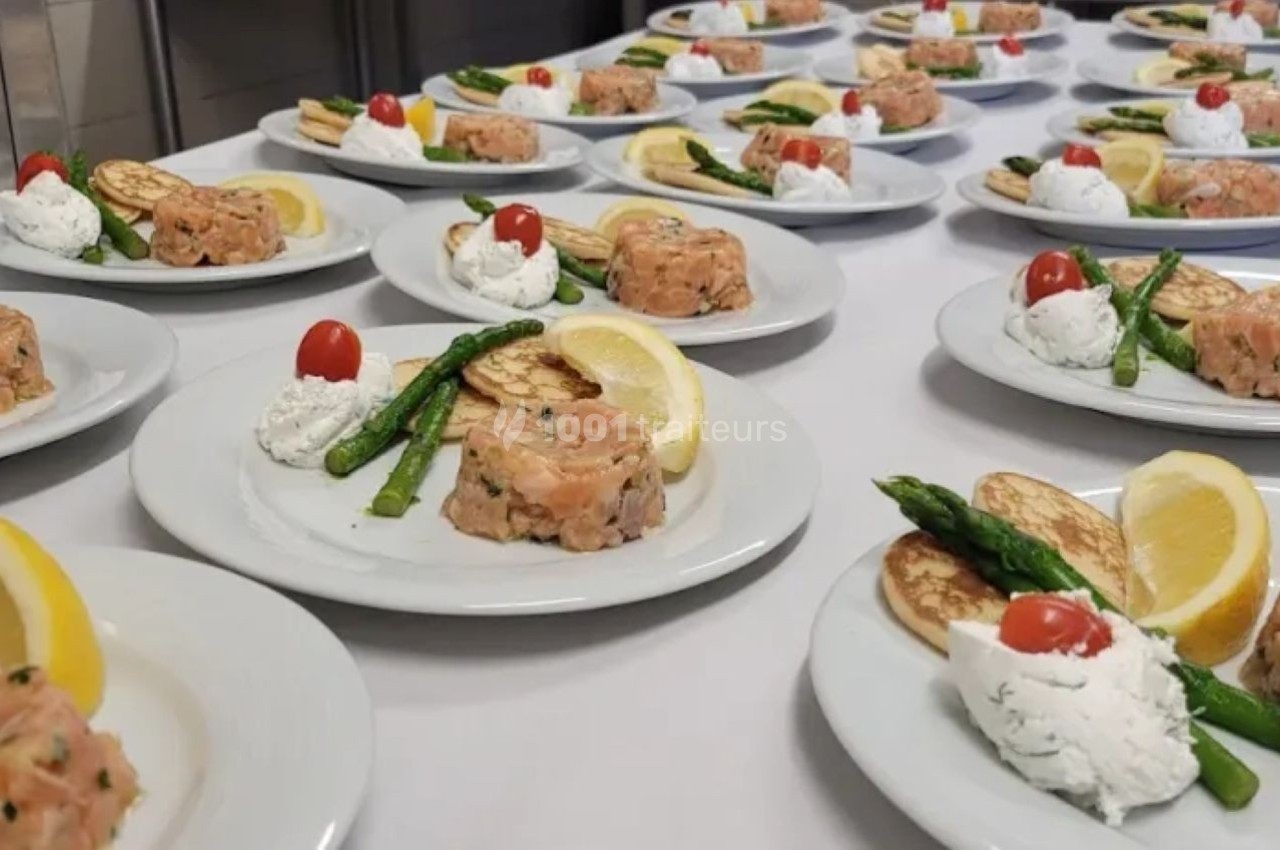 Traiteur Vb Traiteur Gradignan #1 Assiettes dressées avec tartare de saumon, asperges, crème, blinis, citron et tomate cerise sur une table blanche.