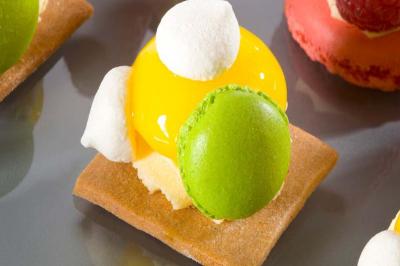 Traiteur La Sellerie Traiteur Thivars #5 Pâtisserie composée d'un biscuit, d'une crème jaune brillante, de meringues blanches et d'un macaron vert.
