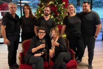Un groupe de personnes pose devant un sapin de Noël décoré, deux d'entre elles assises sur des fauteuils rouges.