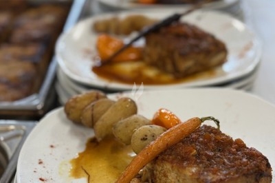 Assiette de viande braisée accompagnée de carottes glacées et pommes de terre, servie sur une table de buffet.