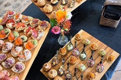 Plateaux en bois garnis de bouchées apéritives variées et colorées, disposés sur une table noire avec des décorations…