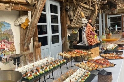 Buffet varié avec verrines, brochettes et plats disposés sur une table blanche dans un décor rustique en bois.
