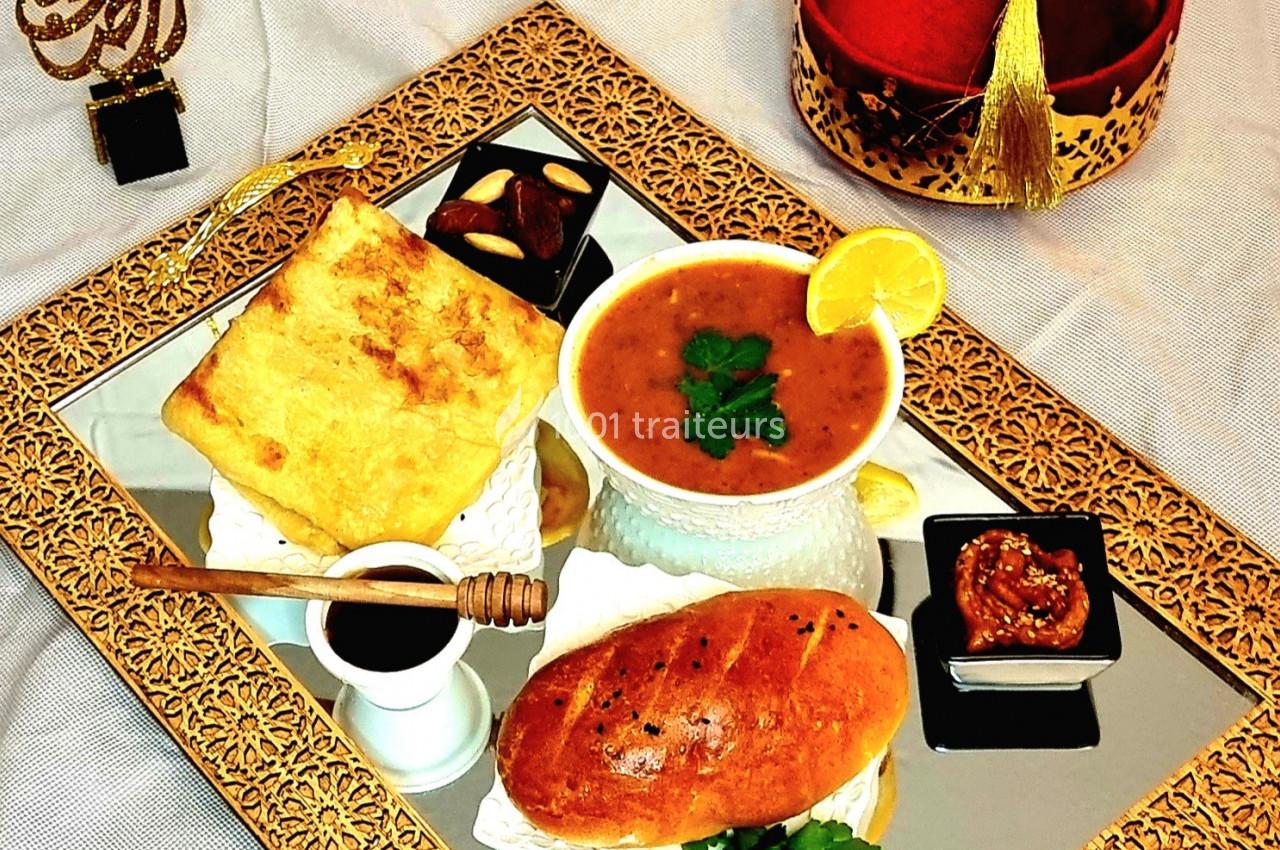 Traiteur Traiteur Sable d'Orient Rumilly #1 Plateau doré avec soupe, pain, miel, fromage, confiture et chapeau rouge décoratif en arrière-plan.