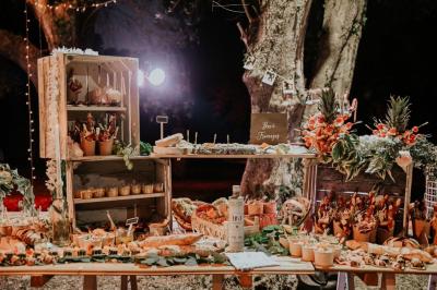 Traiteur Lorette Traiteur Antibes #5 Buffet rustique en extérieur avec étals en bois, décorations florales et mets variés sous un éclairage chaleureux.
