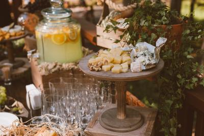 Traiteur FB Traiteur Garancières #3 Plateau en bois avec fromages variés, noix et raisins, entouré de verres et d'une jarre de citronnade en arrière-plan.