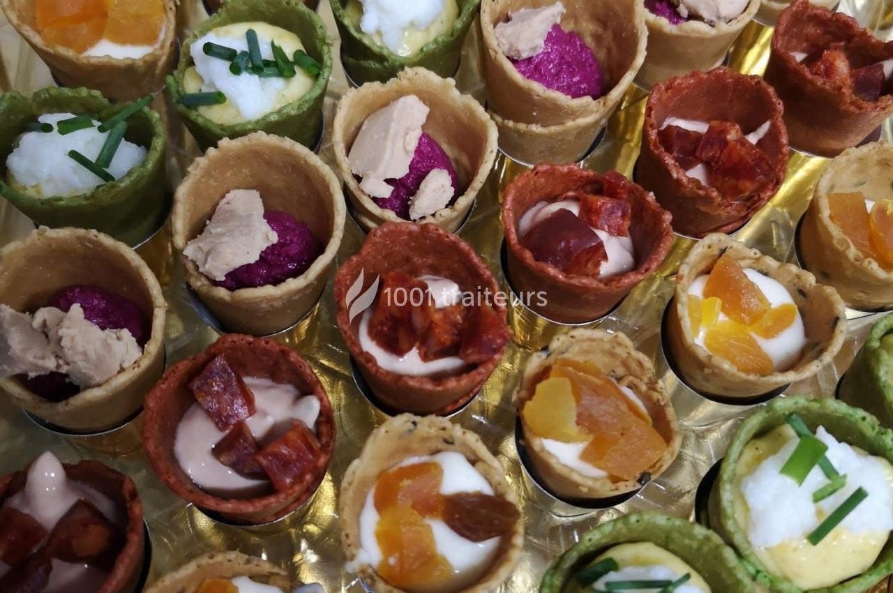 Traiteur L'Atelier de Nicolas Frontignan #1 Assortiment de mini-cornets colorés garnis de mousse, légumes, fromage et herbes fraîches, présenté sur un plateau.