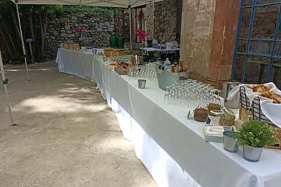 Traiteur L'Atelier de Nicolas Frontignan #4 Tables dressées en extérieur avec nappes blanches, contenant verres, paniers de pain et divers éléments pour un buffet.