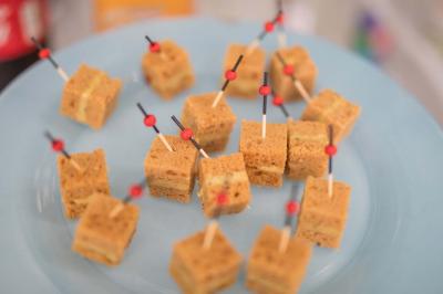 Carrés de gâteau surmontés de cure-dents rouges et noirs, disposés sur une assiette bleue.