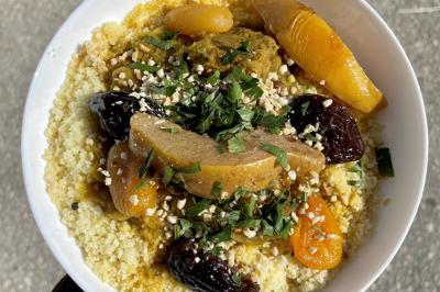 Traiteur Dihya Marseille 13 #4 Assiette de couscous garnie de légumes, fruits secs, viande et herbes fraîches, servie sur une table en extérieur.