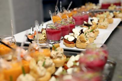 Assortiment de verrines et bouchées apéritives colorées disposées sur des plateaux lors d'un buffet.