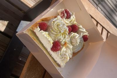 Traiteur Comptoir des Saveurs  Saint-Martin-d'Uriage #5 Part de tarte garnie de crème chantilly, framboises fraîches et éclats de pistache, présentée dans une boîte en carton.