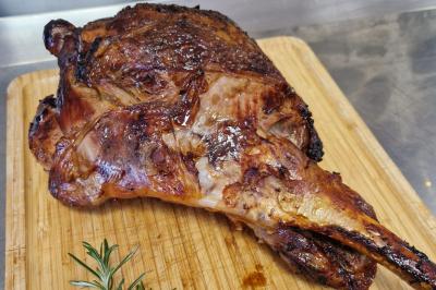Traiteur Comptoir des Saveurs  Saint-Martin-d'Uriage #4 Gigot d'agneau rôti posé sur une planche en bois, accompagné d'une branche de romarin.