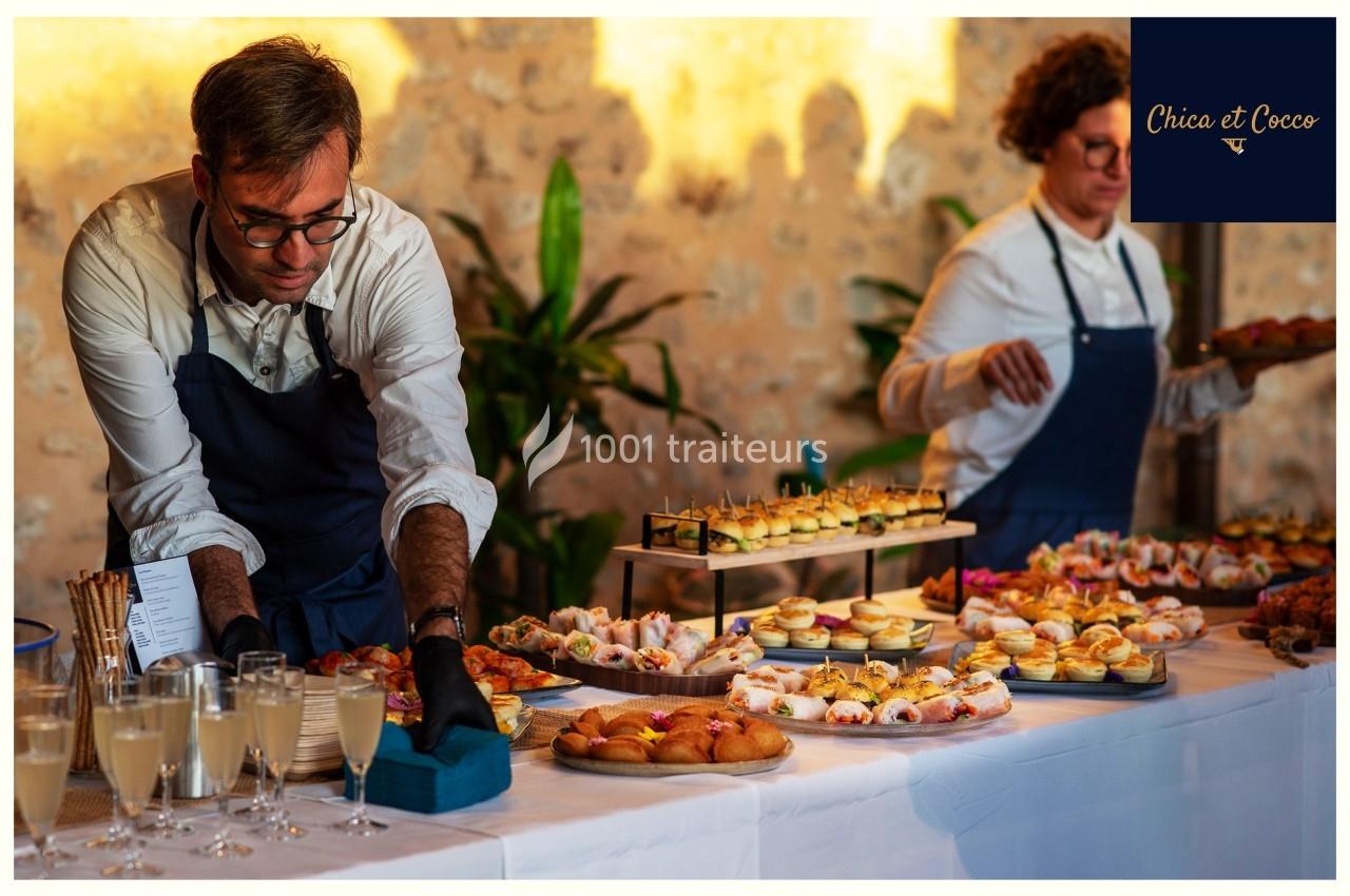 Un serveur dispose des plats sur une table garnie de bouchées et de boissons lors d'un buffet.
