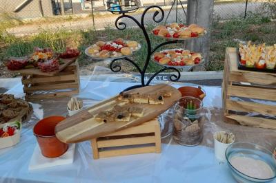 Buffet en extérieur avec plateaux de tapas, verrines, fruits et pain, disposés sur des caisses en bois.