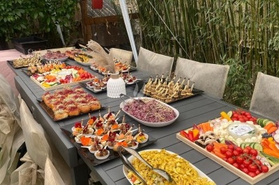 Buffet varié disposé sur une longue table sous une tente, avec plats colorés, salades, amuse-bouches et décor ’Just Married’.