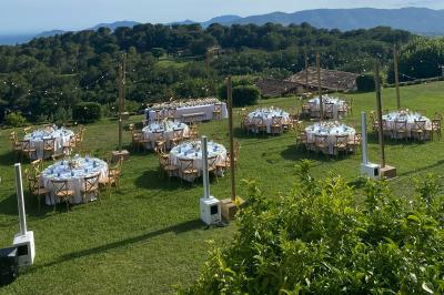 Traiteur Boeuf Traiteur Nice #4 Tables rondes dressées pour un événement en plein air sur une pelouse, avec vue sur des collines verdoyantes.