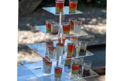 Présentoir en plexiglas avec plusieurs verrines colorées disposées sur plusieurs niveaux en extérieur.