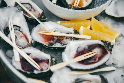 Huîtres ouvertes servies sur de la glace avec des quartiers de citron et des piques en bois.