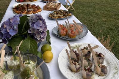 Buffet en plein air avec divers plats et verrines sur une table blanche, décorée d'hortensias et de citrons.