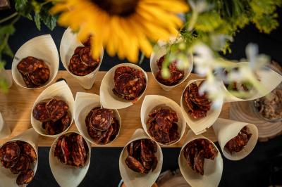 Cornet de saucisson Cônes en bois remplis de tranches de saucisson disposés sur une table, avec un tournesol en premier plan flou.