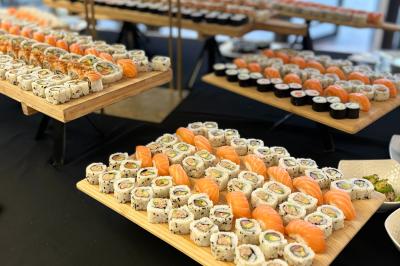 Plateaux de sushis variés disposés sur des tables, comprenant makis, nigiris et autres assortiments.