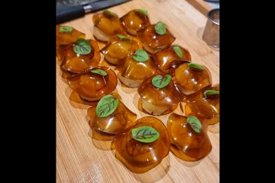 Traiteur Jsch Prestations Culinaires Nanterre #4 Petites bouchées translucides garnies de feuilles vertes, disposées sur une planche en bois.