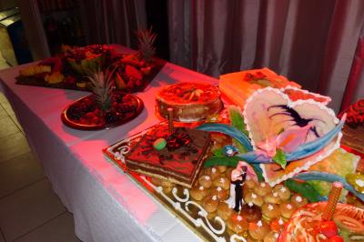 Traiteur Clerence Traiteur Villecresnes #3 Table garnie de desserts variés, dont des gâteaux décorés, des fruits et des pâtisseries, éclairée par une lumière rouge.