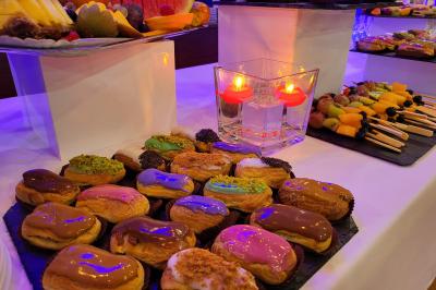 Traiteur Kidira Traiteur  Maromme #3 Plateau d'éclairs colorés, fruits frais et bougies décoratives sur une table de buffet.