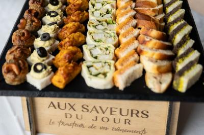 Traiteur Aux Saveurs du Jour Chemillé #3 Plateau de canapés variés comprenant des bouchées salées, roulés et mini-sandwichs présentés sur un support en bois.