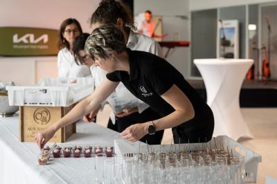 Traiteur Aux Saveurs du Jour Chemillé #5 Une femme dispose des verrines sur une table lors d'un événement, avec d'autres personnes en arrière-plan.