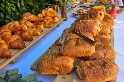 Plateau de viennoiseries comprenant pains au chocolat et croissants, disposé sur une table décorée de fleurs.