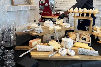 Plateau de fromages variés disposés sur des planches en bois, accompagné de verres de vin rouge.