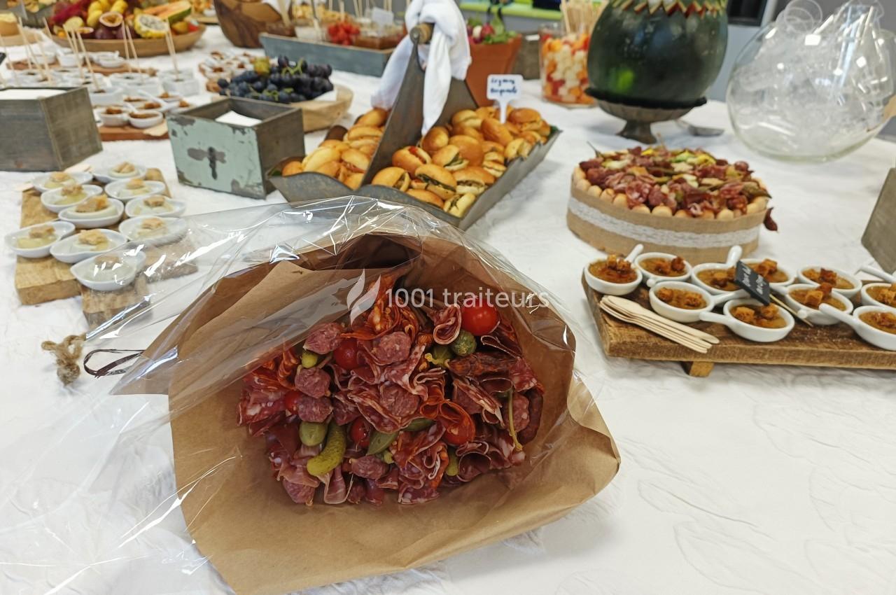 Plateau de buffet avec un bouquet de charcuterie au premier plan, entouré de divers amuse-bouches et desserts.