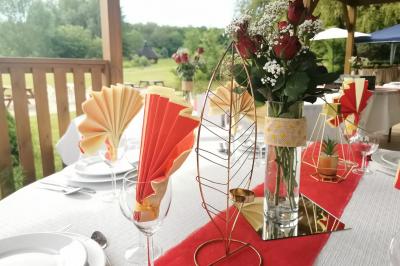 Traiteur Iles en Fete  Magny-les-Hameaux #5 Table décorée pour un événement avec nappes blanches, chemin de table rouge, fleurs et pliages de serviettes colorés.