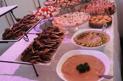 Traiteur Iles en Fete  Magny-les-Hameaux #3 Buffet avec brochettes de viande, verrines, pains garnis et sauces présentés sur une table blanche.