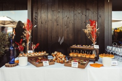 Buffet avec plateaux de bouchées variées, pains, verrines et décorations florales sur une table blanche.