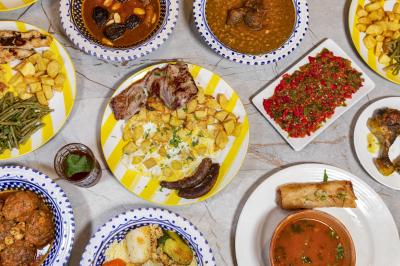 Assortiment de plats variés comprenant viandes, légumes, pommes de terre et sauces, disposés sur une table.