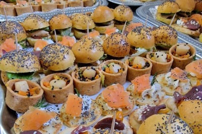 Traiteur Le Quai Fleuri Les Villages Vovéens #3 Plateaux garnis de bouchées variées, incluant mini-burgers, canapés au saumon et amuse-bouches garnis de graines.