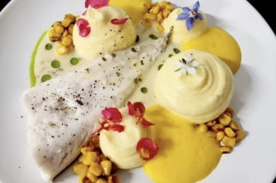 Traiteur Adquat Traiteur Nousty #3 Filet de poisson blanc accompagné de purées, maïs grillé et fleurs comestibles sur une assiette blanche.