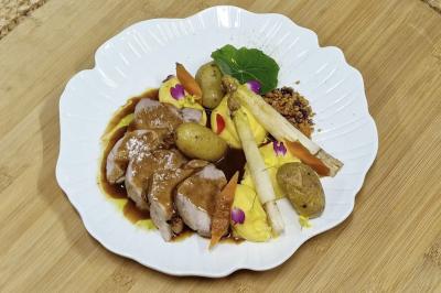 Traiteur Adquat Traiteur Nousty #5 Assiette de viande tranchée avec sauce, pommes de terre, asperges, purée et décorations florales sur une assiette blanche.
