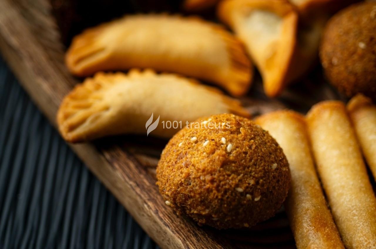 Traiteur La Beyrouthine  Roquebrune-Cap-Martin #1 Assortiment de snacks salés comprenant des samoussas, des falafels et des rouleaux croustillants sur un plateau en bois.