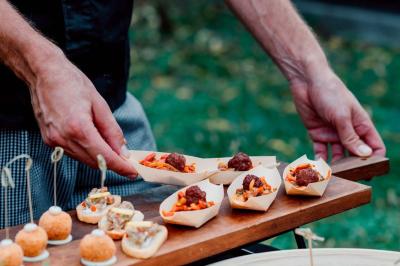 Traiteur Mas de Baumes Ferrières-les-Verreries #3 Un serveur présente des amuse-bouches dans des barquettes en bois, composés de boulettes de viande et de garnitures colorées.