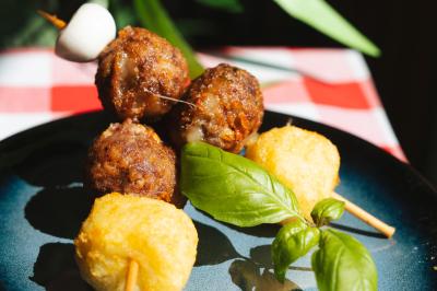 Traiteur Pasta Da Nonna Mia Bouc-Bel-Air #3 Brochettes avec boulettes de viande, fromage frit et feuille de basilic, servies sur une assiette bleue.