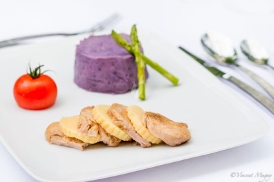 Traiteur Traiteur Benoit Bruley Épagny #1 Assiette avec magret de canard tranché, purée violette, asperges vertes et tomate cerise, servie sur une table dressée.